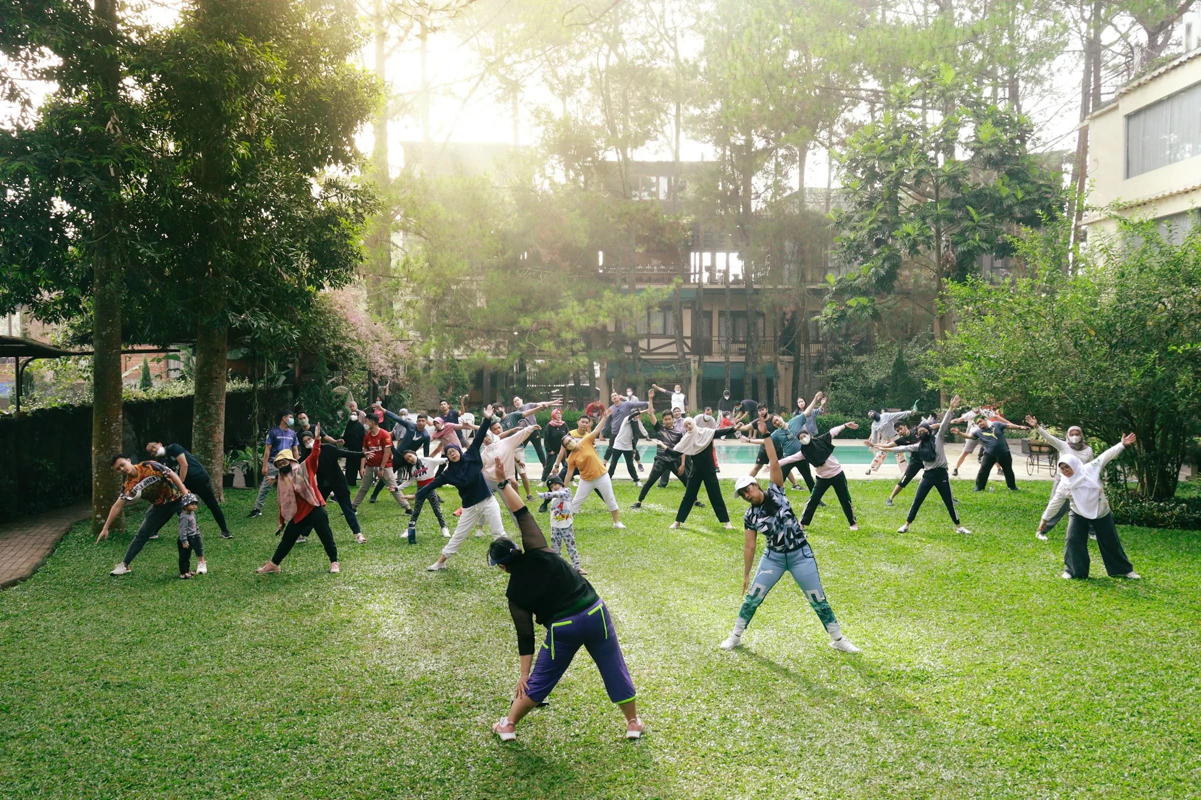 An outdoor group fitness class stretching on a sunlit lawn