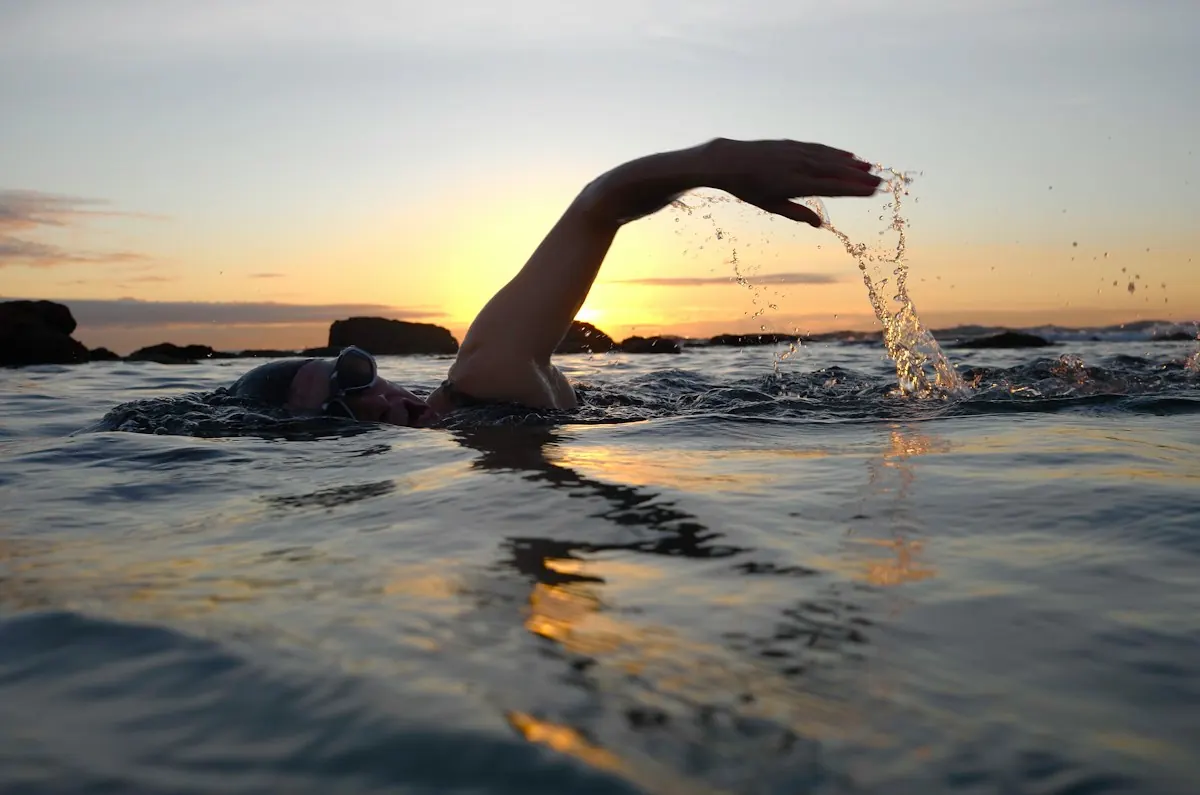 An open-water swimmer mid-stroke at sunset